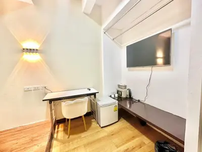a room with a table and a tv and a desk at ABC SO Hotel Bangkok in Bangkok