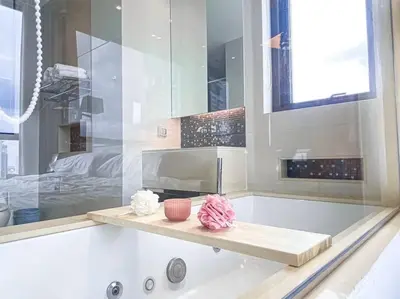 a bathroom with a bath tub with a sink at Grand Modern 2BR - Ultra Fast WiFi - Phrom Phong in Bangkok