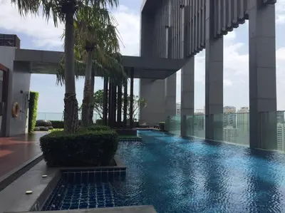 a swimming pool in the middle of a building with palm trees at Grand Modern 2BR - Ultra Fast WiFi - Phrom Phong in Bangkok