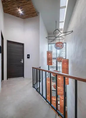a hallway with a staircase with orange chandeliers at Siam Shelter Bangkok in Bangkok