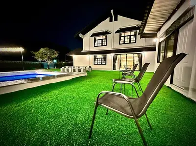 a yard with two chairs and a house with green grass at Number3 Poolvilla Bangkok in Lat Krabang