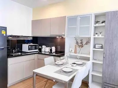 a kitchen with a white table and white chairs at Expansive Modern - BTS Phrom Phong - Ultra Fast WiFi in Khlong Toei