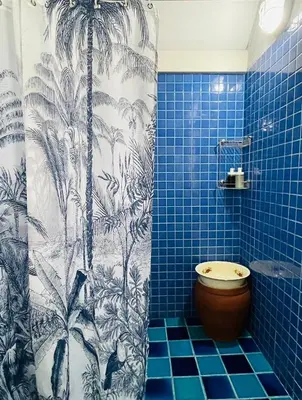 a blue tiled bathroom with a shower with a toilet at The Backyard 28 in Khlong Toei