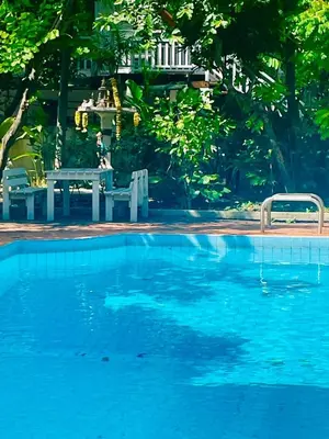 a large blue swimming pool with a table and chairs at The Backyard 28 in Khlong Toei