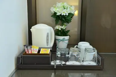 a tray with a coffee maker and a vase with flowers at The Prestige Nana in Bangkok