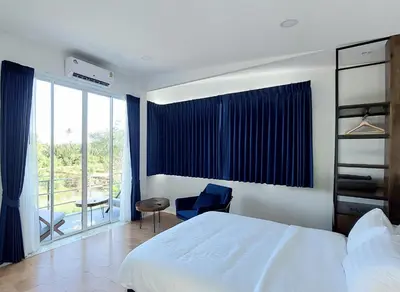 a bedroom with a bed and a chair and a window at Green Lung Pool Villas Bangkok in Bang Krasop