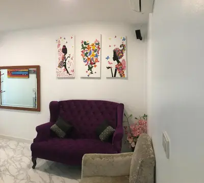a living room with a purple couch and four paintings at เดอะวิลล่า71 รีสอร์ท in Ban Zong Katiam