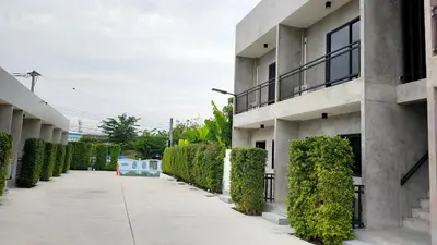 an empty sidewalk in front of a building with bushes at The Loftel Resort in Bangkok