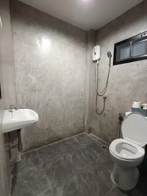 a bathroom with a shower and a toilet and a sink at The Loftel Resort in Bangkok
