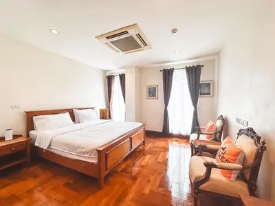a bedroom with a bed and a couch and a chair at Chez Moi Bangkok Private Executive Residence Sukhumvit 26 in Khlong Toei