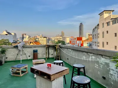 a table and chairs on a rooftop with a view of a city at Baan KhaoSoi - Private room in a rooftop hostel 3rd floor in Khlong San
