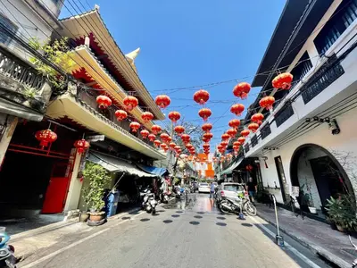 a street with red lanterns hanging from buildings at Baan KhaoSoi - Private room in a rooftop hostel 3rd floor in Khlong San