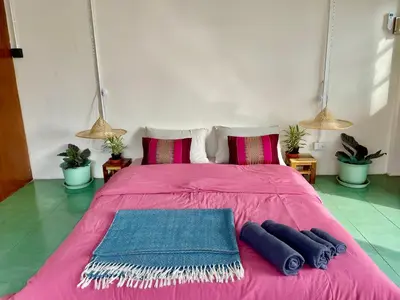 a pink bed with two pillows and two mats on it at Baan KhaoSoi - Private room in a rooftop hostel 4th floor in Khlong San