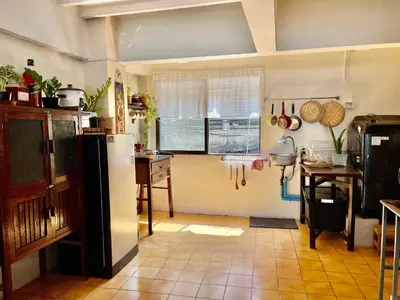 a kitchen with a refrigerator and a table at Baan KhaoSoi - Private room in a rooftop hostel 4th floor in Khlong San