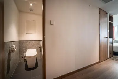 a bathroom with a toilet next to a door at Sotetsu Grand Fresa Bangkok in Bangkok