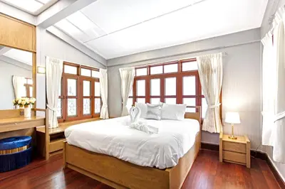 a bedroom with a bed and a desk and windows at Sathorn Private Pool Villa in Bangkok