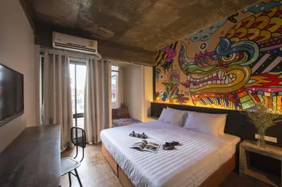 a bedroom with a bed with a painting on the wall at Cacha Hotel in Bangkok