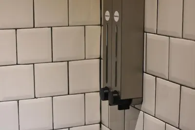 a bathroom stall with white tiled walls and a door at Cacha Hotel in Bangkok