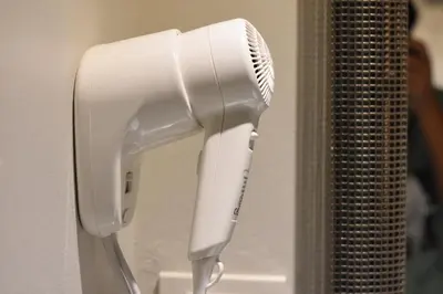 a white hairdryer hanging on a wall at Cacha Hotel in Bangkok