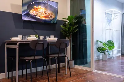 a dining room with a table with chairs and a tv on the wall at A4 Cosy Twin large beds - Silom in Bangkok