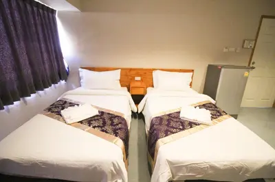 a hotel room with three beds and a window at L'Hotel Bangkok in Bangkok