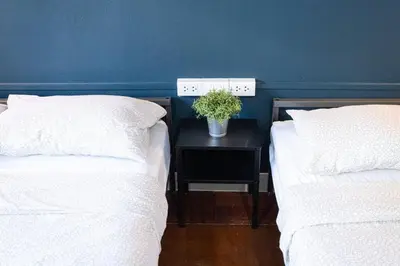 two beds with white sheets and a plant on a night stand at A3 Large Room, Full Facilities in Bangkok