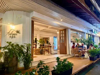 a group of people sitting outside of a restaurant at Unplugged at Bangrak Design Hostel in Bangkok
