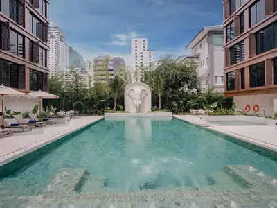 a swimming pool in the middle of a building with a fountain at Nysa Hotel Bangkok Sukhumvit 11 in Bangkok