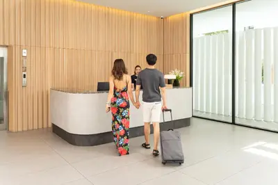 a man and woman standing in an airport with their luggage at Saan Hotel Sathorn in Bangkok