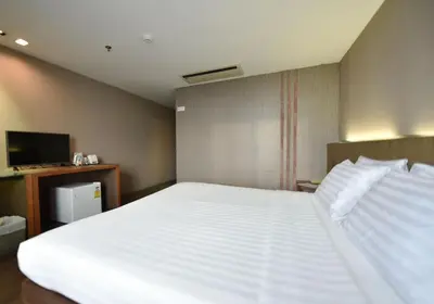 a bedroom with a large white bed and a television at Bangkok City Hotel in Bangkok