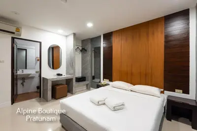 a bedroom with a white bed and a bathroom at Alpine Boutique Pratunam in Bangkok