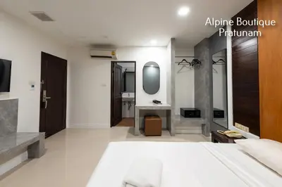 a bedroom with a large bed and a mirror at Alpine Boutique Pratunam in Bangkok