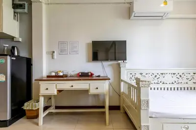 a kitchen with a desk and a tv on the wall at Narastay @ Phrom Phong in Bangkok