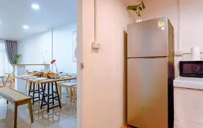 a kitchen with a refrigerator and a table with chairs at Ratchada Retreat Bespoke Urban Villa 3 in Bangkok