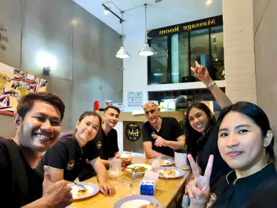 a group of people sitting at a table eating food at BM Loft On Nut & Massage in Bangkok