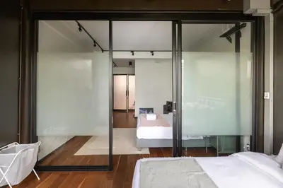 a bedroom with glass walls and a bed in a room at MIQ Ekkamai2 3BR Designer home Oval Bathtub 15pax in Bangkok