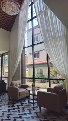 a living room with couches and a table and windows at โรงแรมเซเว่นรัชดา S7VEN RATCHADA in Bangkok