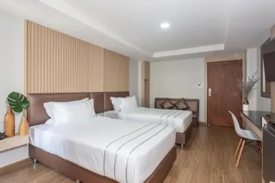 a hotel room with two beds and a desk at โรงแรมเซเว่นรัชดา S7VEN RATCHADA in Bangkok