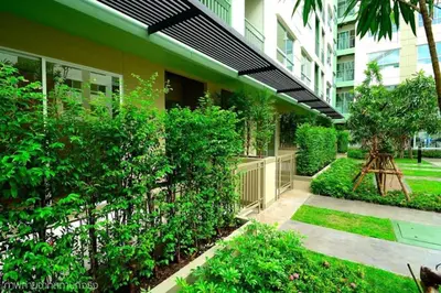 a garden in front of a building with bushes at Fully Furnished Studio Apartments in Bangkok