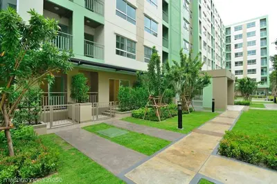 a courtyard in a apartment building with trees and grass at Fully Furnished Studio Apartments in Bangkok