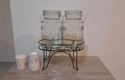 a glass jar on a metal stand with two cups at Chaiwat Hostel in Bangkok
