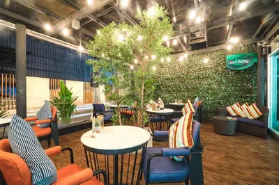 a restaurant with tables and chairs and a green wall at Citrus Sukhumvit 11 by Compass Hospitality in Bangkok