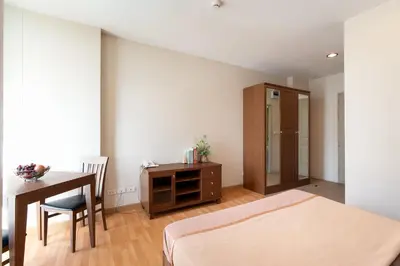a bedroom with a bed and a desk and a table at 181 Ekkamai Apartment in Bangkok