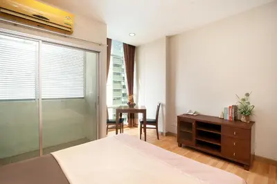 a bedroom with a bed and a desk and a window at 181 Ekkamai Apartment in Bangkok