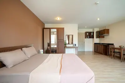 a bedroom with a large white bed and a kitchen at 181 Ekkamai Apartment in Bangkok