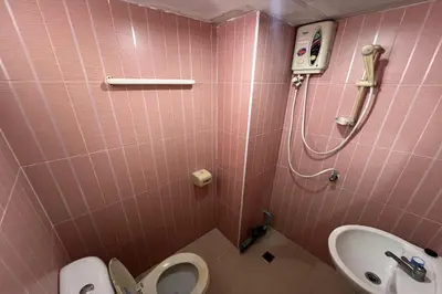 a pink bathroom with a toilet and a sink at Phongsathon Mansion in Bangkok