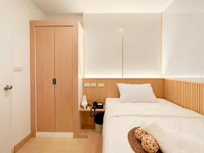 a small bedroom with a bed and a cabinet at Thrive Hotel in Bangkok