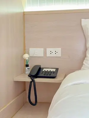 a phone is sitting on a table next to a bed at Thrive Hotel in Bangkok