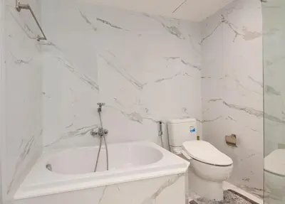 a white bathroom with a toilet and a tub at The Elite @ Thong Lor 25 in Bangkok