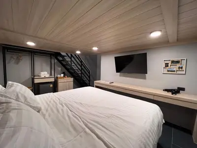 a bedroom with a large bed and a flat screen tv at Chainam-Charmchuree residences cafe and spa in Ban Bang Bua Thong